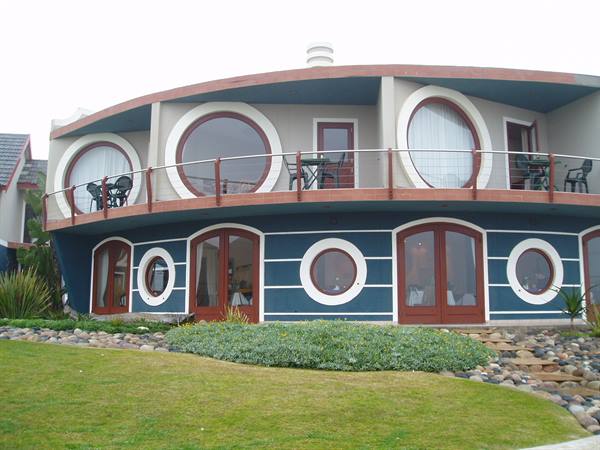 Ship-shaped building with round porthole windows and balconies above green lawn