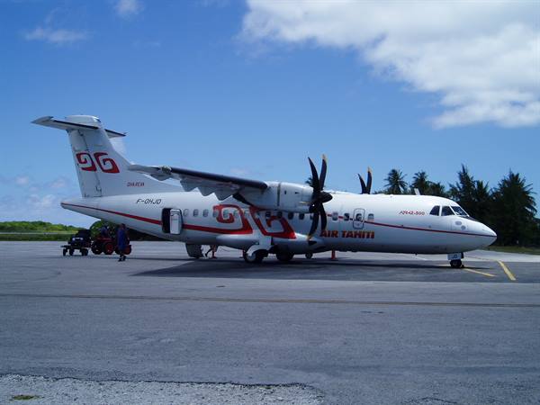 Air Tahiti turboprop plane parked on the tarmac, palm trees and blue sky