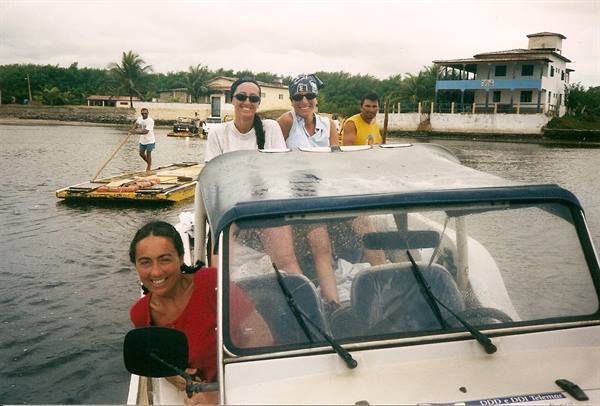 Four smiling tourists riding an amphibious buggy on a river near a wooden raft