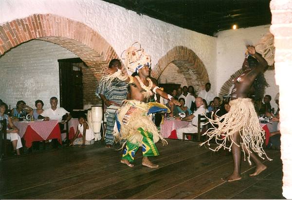 Traditional dancers perform for seated tourists under brick arches