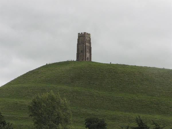 Glastonbury Tor stone tower atop grassy hill under grey sky