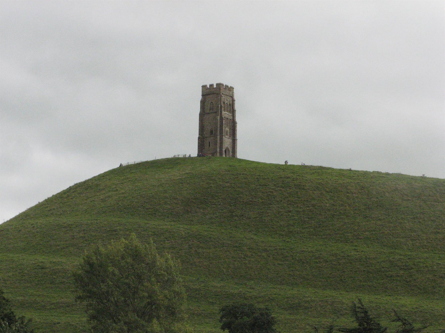 Glastonbury Tor stone tower atop grassy hill under grey sky