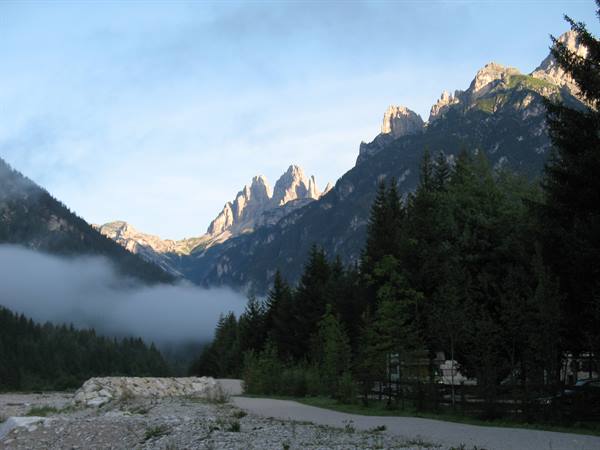 Dolomite peaks lit at dawn above firs and fog in the valley