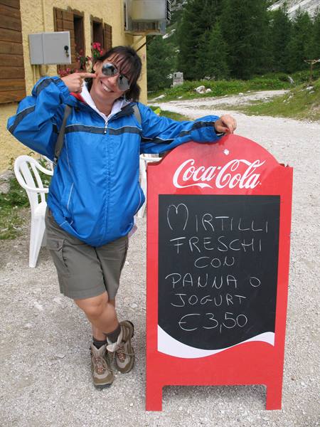 Smiling tourist next to a Coca-Cola sign advertising fresh blueberries