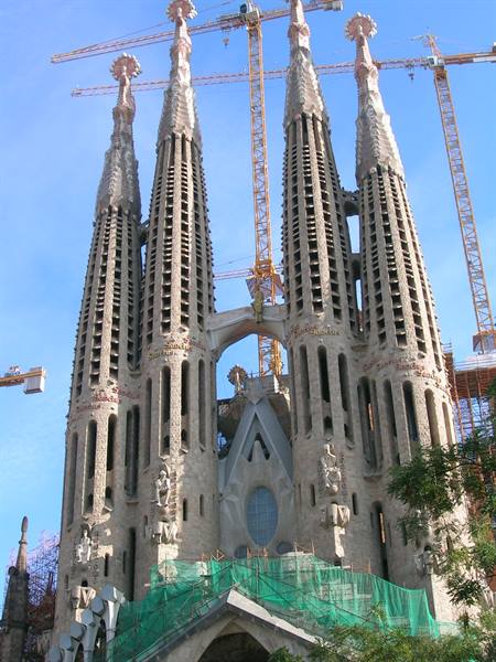 Sagrada Familia in Barcelona, stone towers under construction with cranes, sunlight