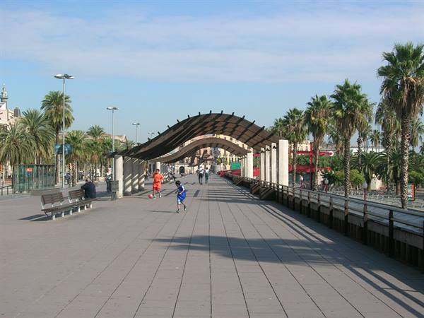 Waved wooden pergola over paved promenade with palms and running children, Barcelona