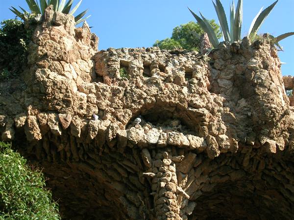 Rough stone structures at Park Güell with agave plants under sunlight