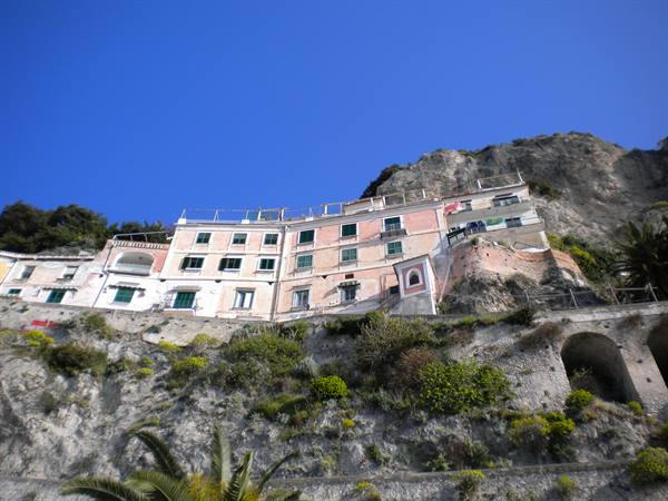 Colorful houses built against the rocky cliff under blue sky