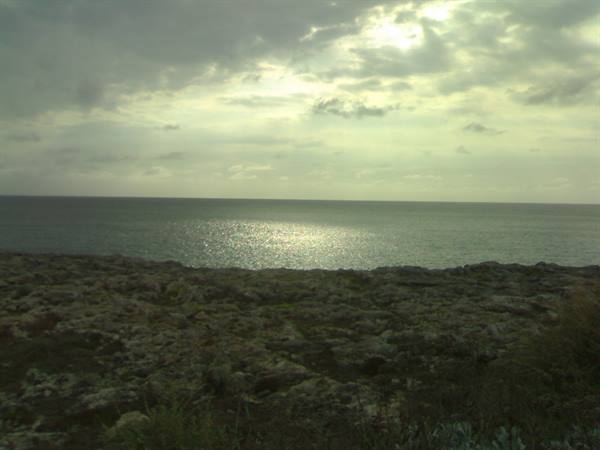 Dark rocks above the shimmering sea beneath grey clouds