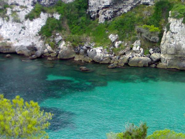 Turquoise water beneath white limestone cliffs and pines, Cala Galdana