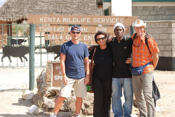 Four tourists posing in front of the Tsavo East park sign