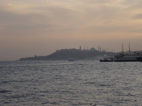 Ferry moored at dock, silhouette of mosques and minarets over Istanbul at dusk