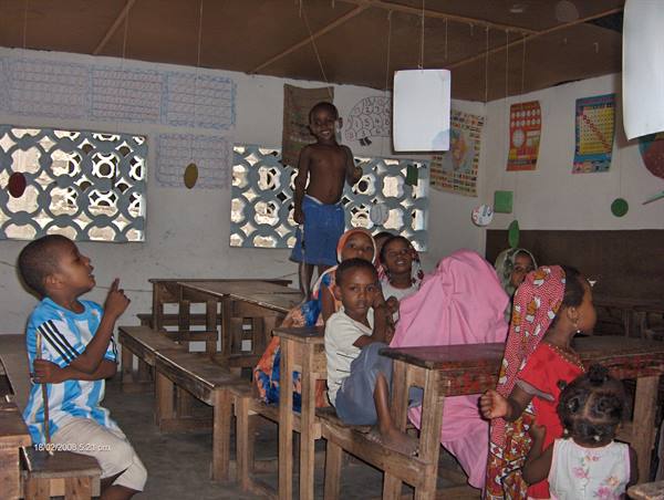 Children in a classroom with wooden desks and decorative walls
