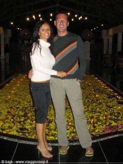 Smiling couple in front of a pool covered with floating flowers and candles
