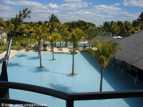 Palm trees in a tropical resort pool, thatched roof and cloudy sky