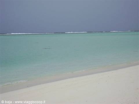 White sand beach and turquoise lagoon with waves breaking on the reef