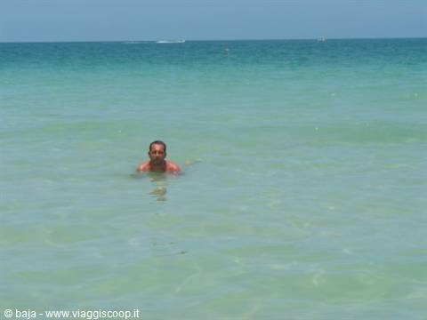 Man swimming in clear turquoise water under bright light
