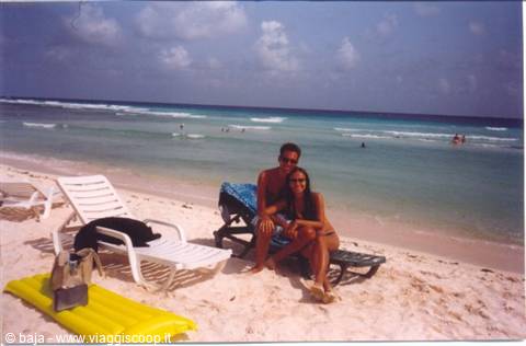 couple sitting on lounge chairs at white sand beach with turquoise sea