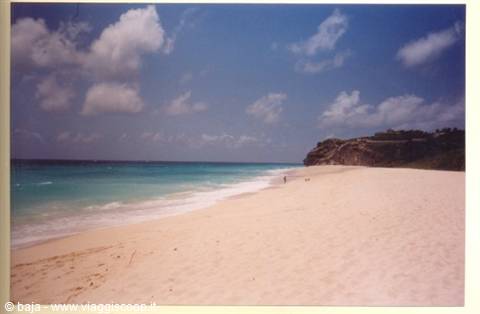 White sand beach, turquoise sea and green rocky headland on the right