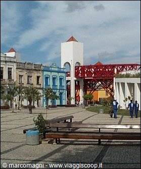 Square with blue colonial buildings, white tower and red iron bridge