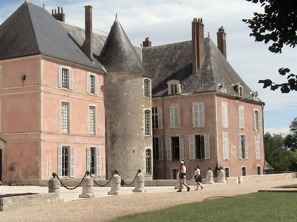 Visitors walk past the pink château with its stone tower