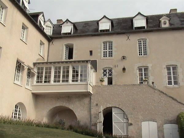 Light stone facade with glazed veranda and arched doorways under grey sky