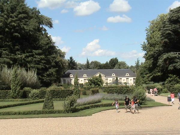 Tourists walk on the gravel path in front of the Château de Chenonceau Orangerie