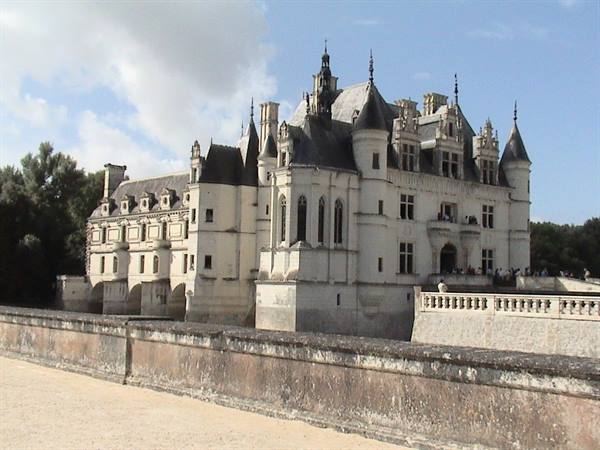 Chenonceau castle in light stone with conical towers above the river