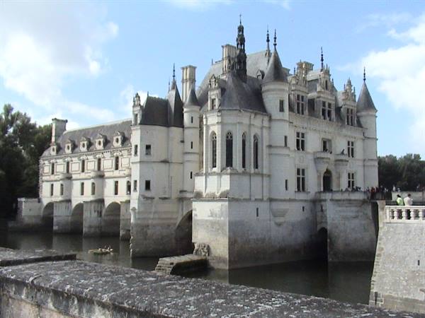 Chenonceau white stone castle built across the river, cloudy sky