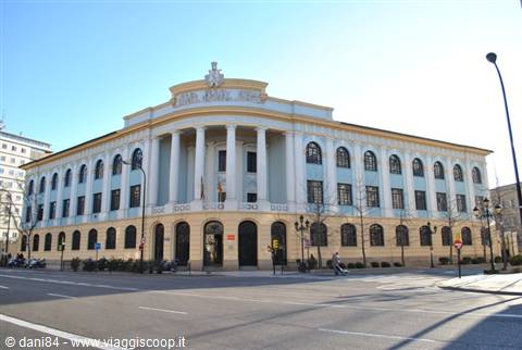 White neoclassical building with columns and arches under blue sky