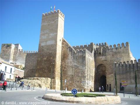 Puerta de Sevilla gate in Carmona, sandstone walls under clear blue sky