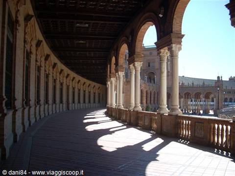 Curved brick arcade with columns in sunlight, Plaza de España in Seville