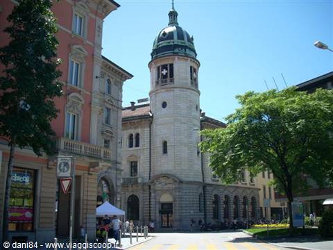 Tower with green dome and clock, pale stone building in Lugano