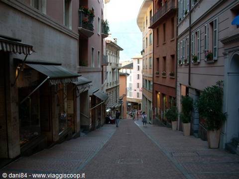Steep street with colorful buildings, awnings and flower balconies, Lugano