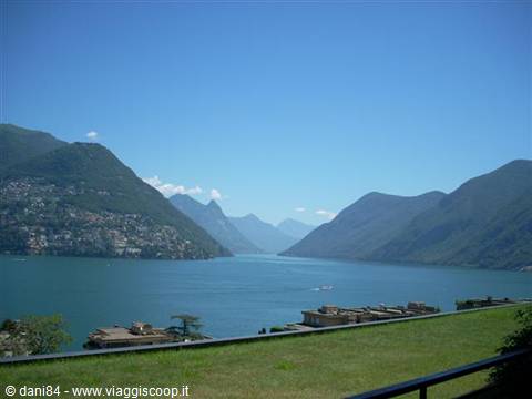 Lake Lugano surrounded by mountains under a clear blue sky