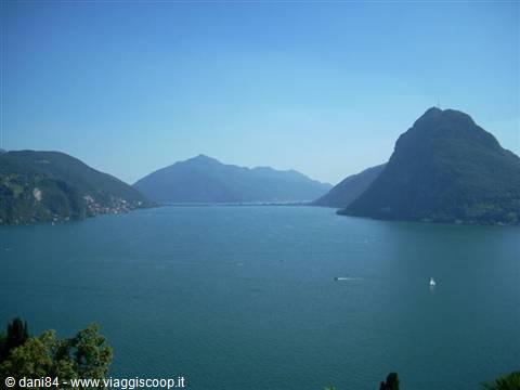 Bay of Lugano with Monte San Salvatore, blue water and boats in sunlight