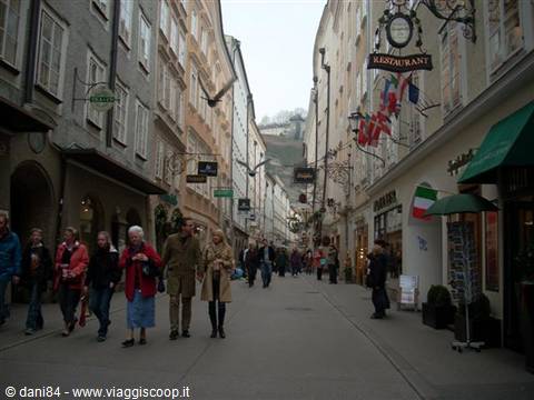Tourists stroll along Salzburg's Getreidegasse among wrought-iron shop signs