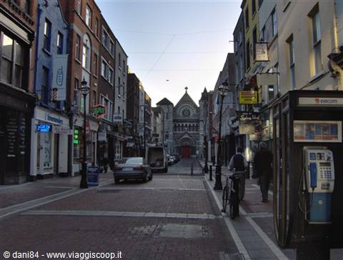 Dublin pedestrian street with cyclist, phone booth and St Ann's Church