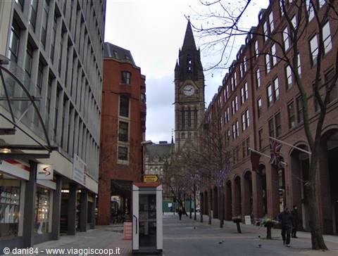 The clock tower of Manchester Town Hall between red brick buildings