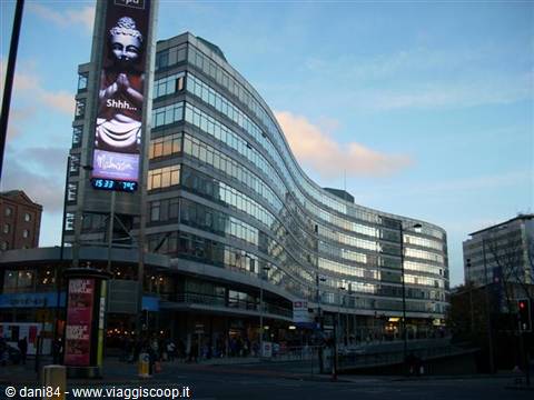 Curved glass office building with lit advertising at Piccadilly Gardens, Manchester