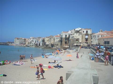 Cefalù beach: swimmers under umbrellas in front of old seaside houses