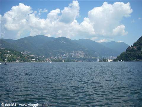 Lake Como, rippling water, green mountains and white clouds above the town