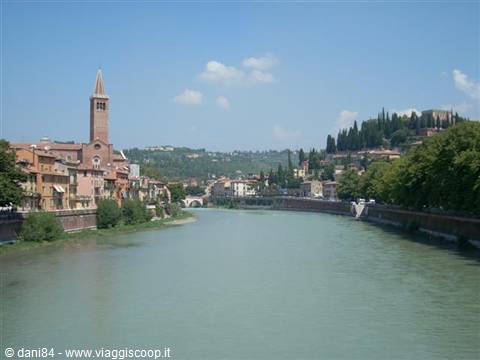The green Adige river flows past red buildings and Sant'Anastasia bell tower, Verona