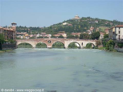 Ponte Pietra brick and stone bridge over the Adige, Verona, with hills and colored houses behind
