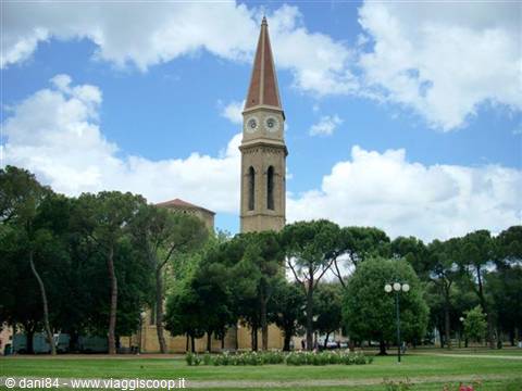 Brick bell tower with red spire rising above Livorno's green gardens