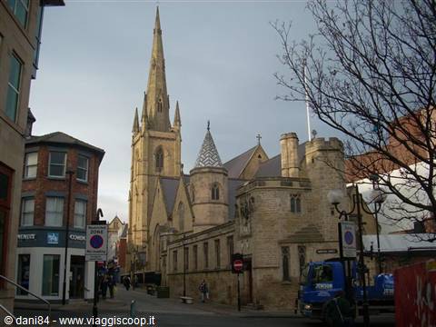 Gothic spire of Sheffield Cathedral above stone buildings and street traffic