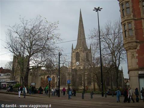 People walk past St Peter Mancroft church in Norwich under a grey sky
