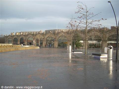 Rain-soaked plaza in front of the stone-arched railway station