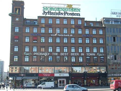 Brick building in Copenhagen with Jyllands-Posten and Carlsberg signs, traffic below