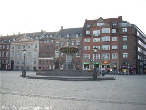 Baroque fountain on paved square in front of colorful buildings, Copenhagen